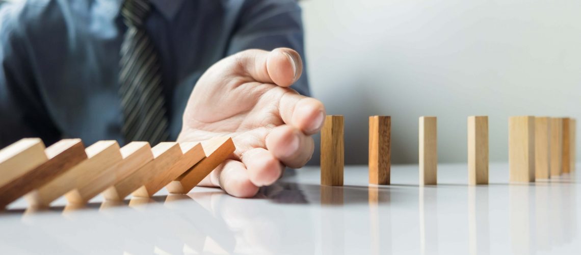 businessman-hand-stop-dominoes-continuous-toppled-or-risk-with-copyspace (1)